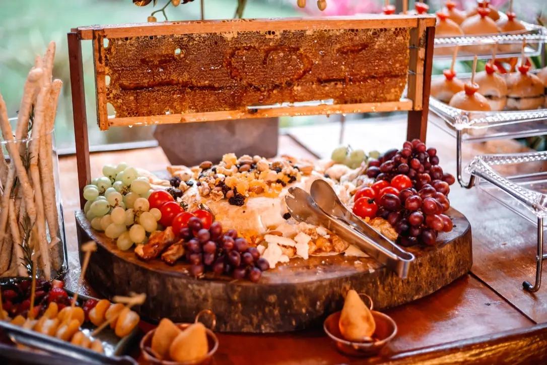 Mesa de frios do buffet, com queijos, uvas e favo de mel