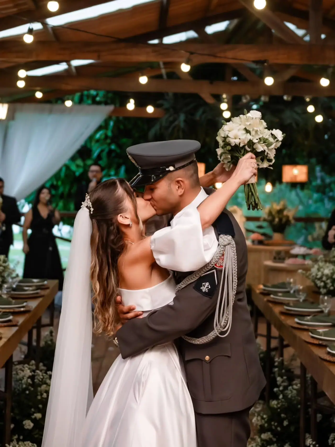 Noivos se beijando ao lado da mesa posta da festa